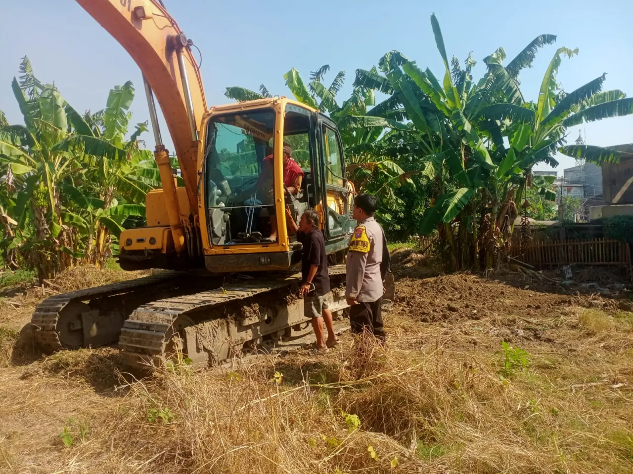 Ket Foto : Percepat Masa Tanam, Polres Pelabuhan Tanjung Perak Kerahkan Ekskavator Olah Lahan Pascapanen. 